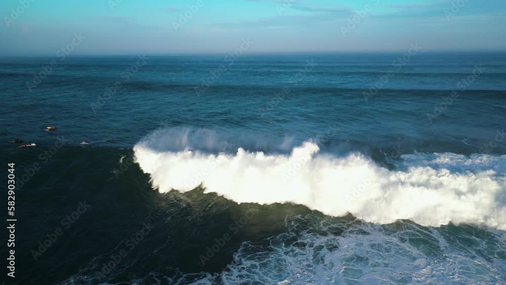 Aerial view of surfers in massive waves in sunny Hawaii - reverse, drone shot Aerial view of surfers in massive waves in sunny Hawaii - reverse, drone shot