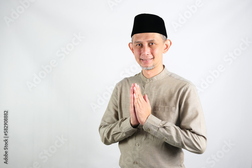 Portrait Asian Moslem Man with greetings and welcoming gestures, smiling face
 photo