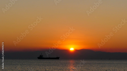 The Graceful Silhouette of a Cargo Ship: Sailing into the Sunset of Thessaloniki's Bay