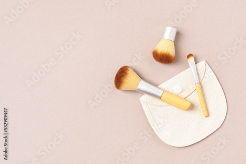 Bamboo cosmetic brushes and cotton bag on beige background. Natural, Eco-friendly make up tools. Copy space.