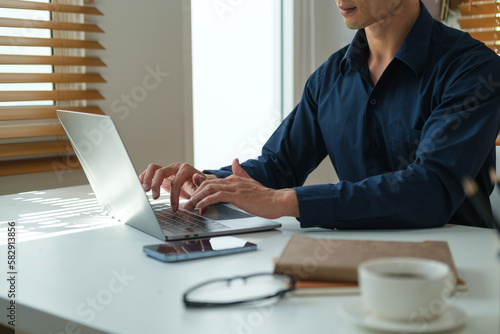 Young businessman hands typing business email on laptop computer at working desk.