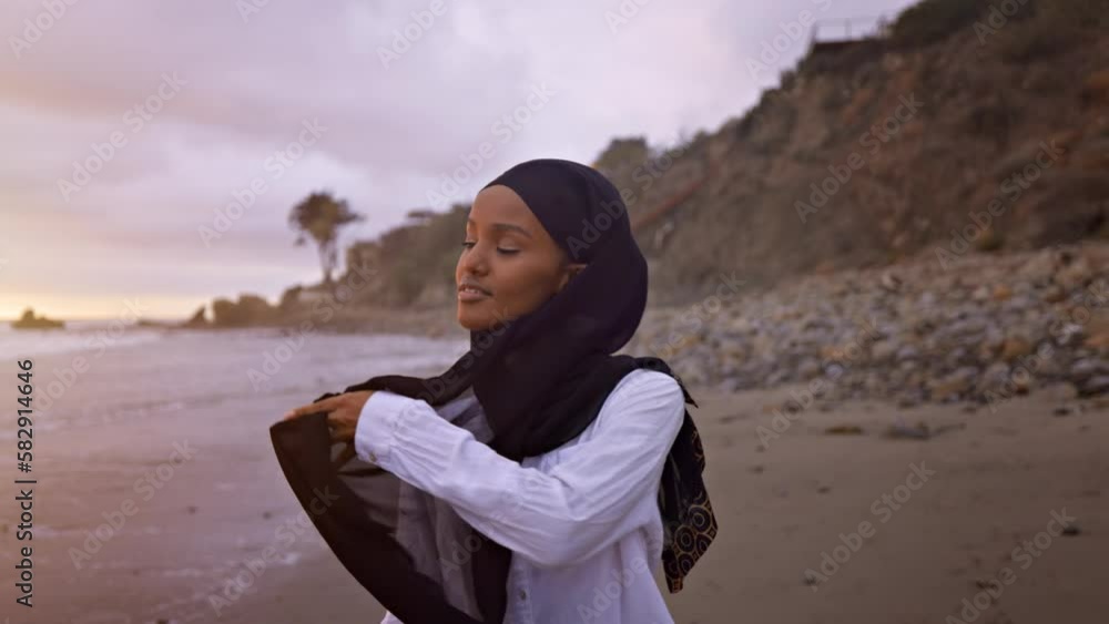 Somali-American woman walking on the beach in Malibu at sunset. Somali-American woman walking on the beach in Malibu at sunset.
