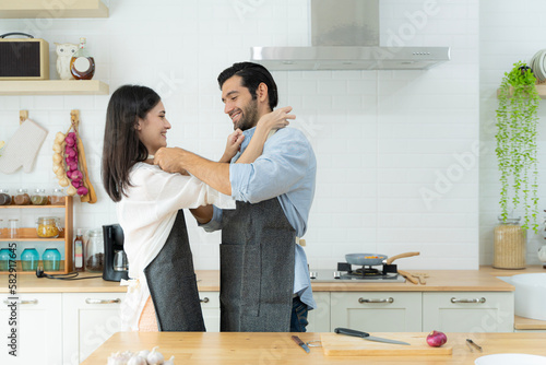 Cooking, together, kitchen, relationship. A couple wears apron to each other to make breakfast.