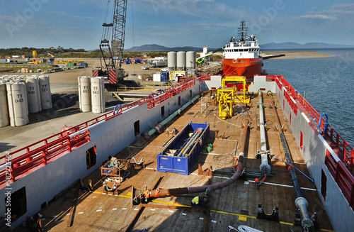 Barry Beach Marine Terminal crane lift a helipad in two sections onto a offshore workboat dockside.ships line up with machinery on deck.
 photo