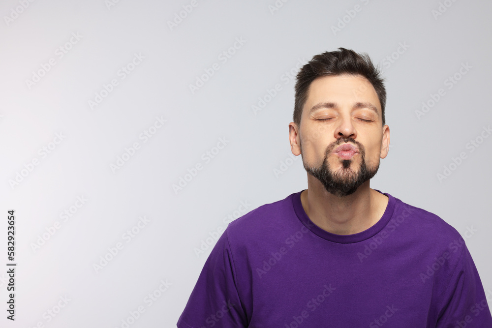 Handsome man blowing kiss on light grey background. Space for text Handsome man blowing kiss on light grey background. Space for text