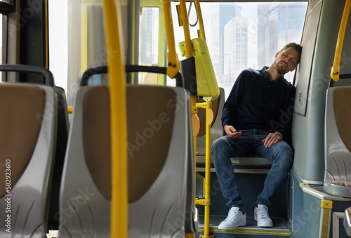 Tired man sleeping while sitting in public transport