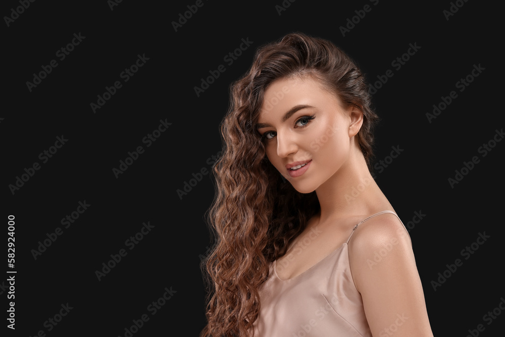 Beautiful young woman with long curly brown hair on black background, space for text Beautiful young woman with long curly brown hair on black background, space for text