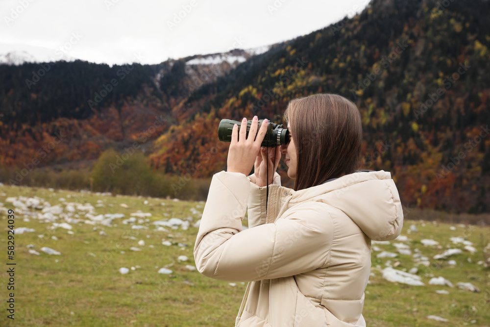 Woman looking through binoculars in beautiful mountains. Space for text Woman looking through binoculars in beautiful mountains. Space for text
