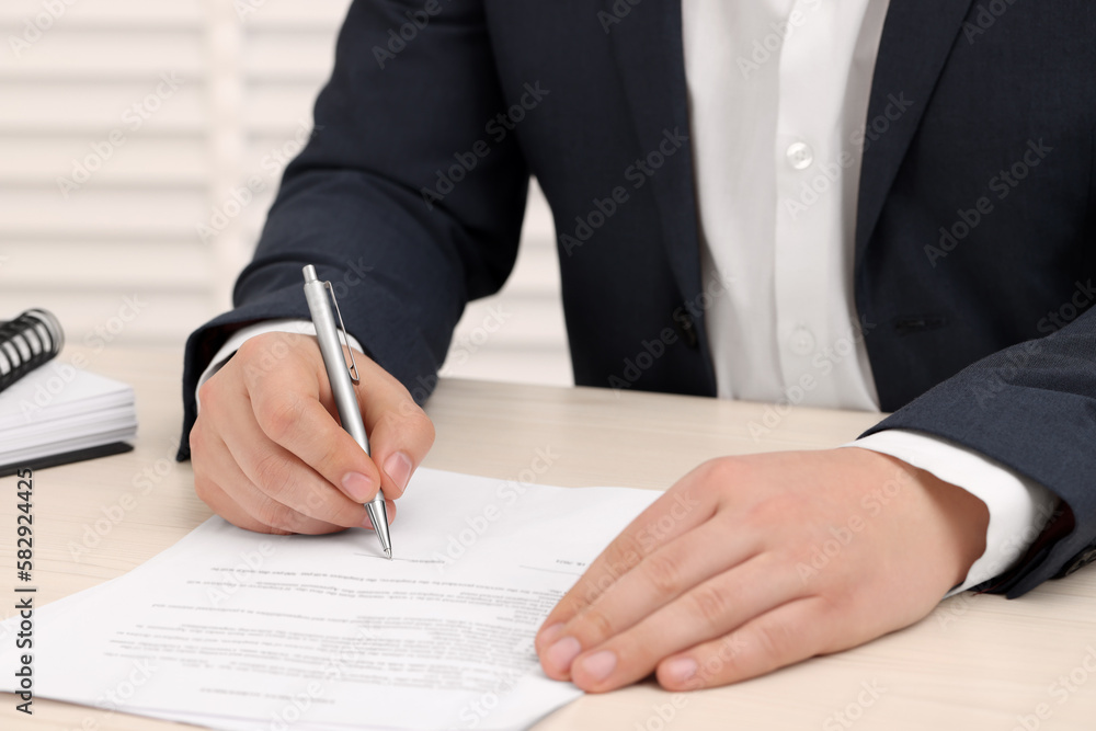 Man signing document at wooden table, closeup Man signing document at wooden table, closeup