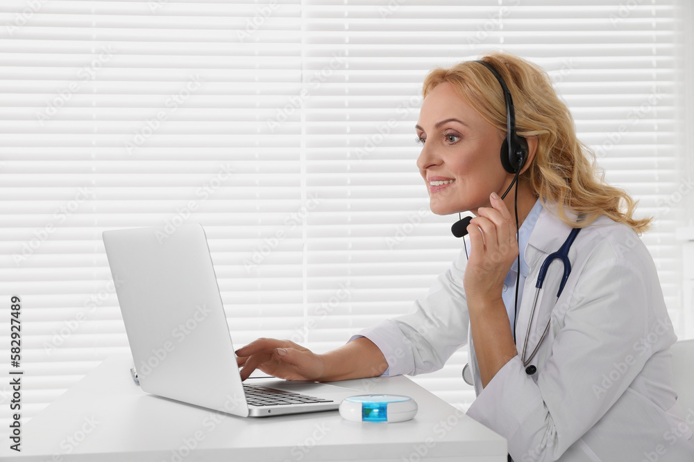 Doctor with laptop and headphones consulting patient in clinic. Online medicine concept Doctor with laptop and headphones consulting patient in clinic. Online medicine concept