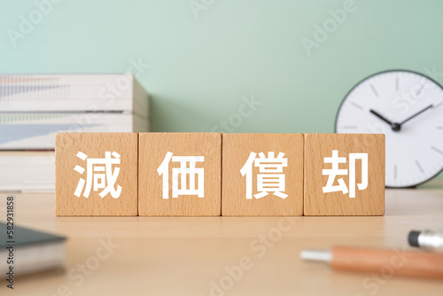 Photos 減価償却と書かれたブロックが置かれたデスク