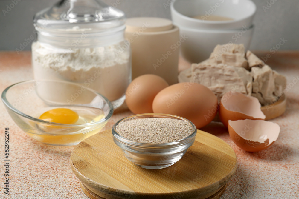 Compressed and dry granulated yeast, flour and eggs on orange textured table Compressed and dry granulated yeast, flour and eggs on orange textured table