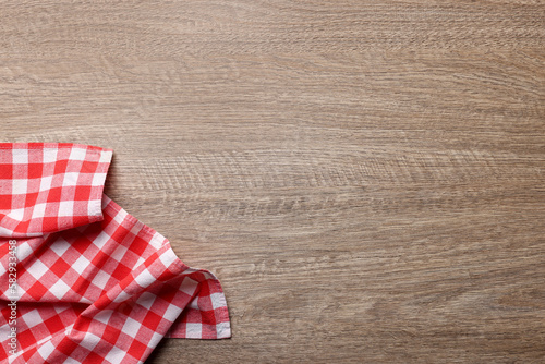Checkered tablecloth on wooden table, top view. Space for text