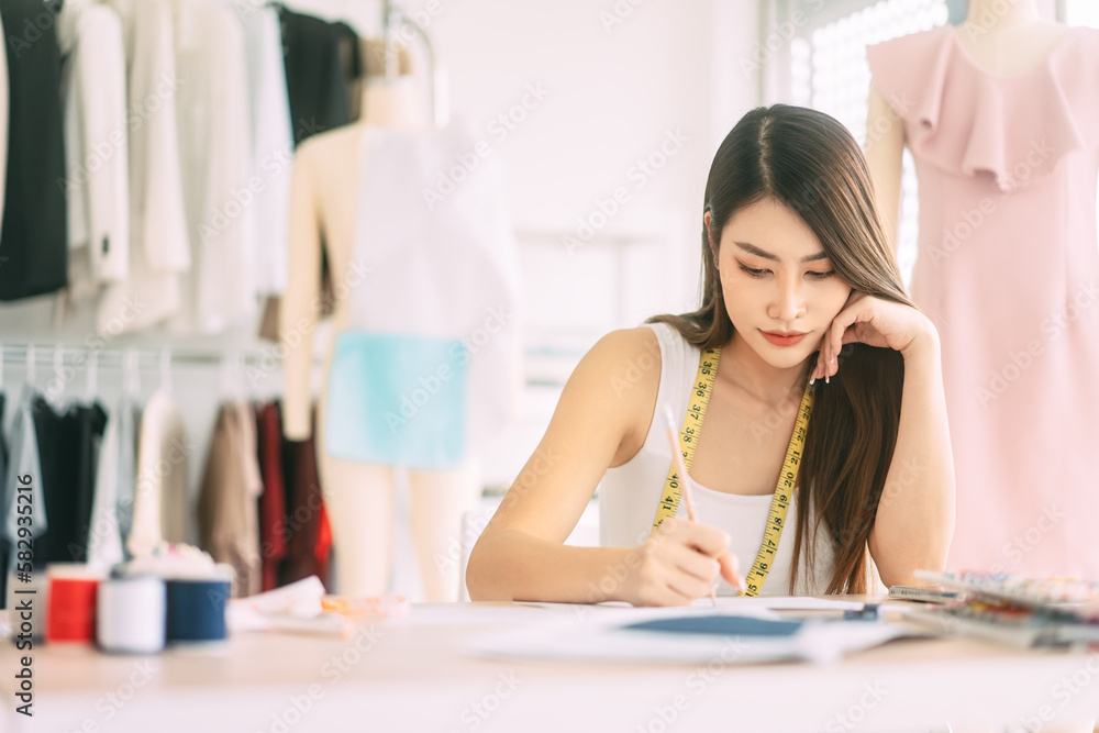 Asian woman designer busy making clothes work or study in fashion design studio Asian woman designer busy making clothes work or study in fashion design studio