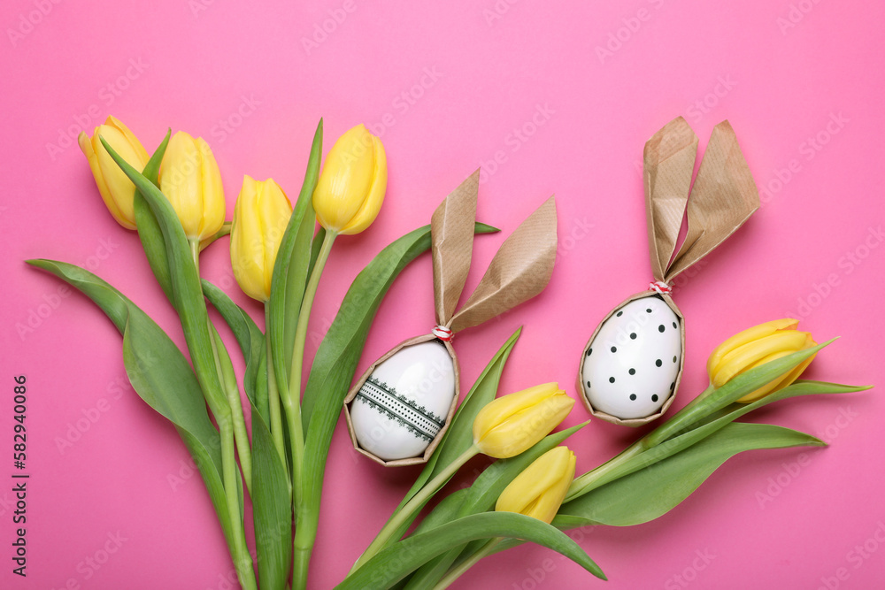 Easter bunnies made of craft paper and eggs among beautiful tulips on pink background, flat lay Easter bunnies made of craft paper and eggs among beautiful tulips on pink background, flat lay