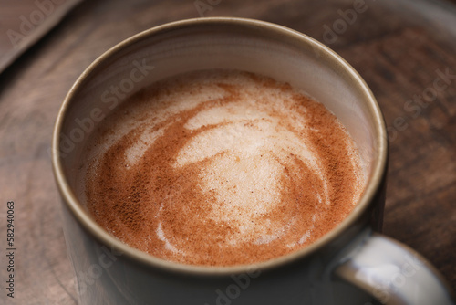 Cup of delicious eggnog on wooden tray, closeup