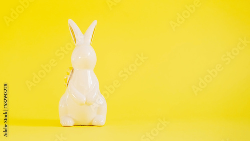 Easter white ceramic rabbit on a yellow background. Festive spring background, happy Easter holidays concept or greeting card