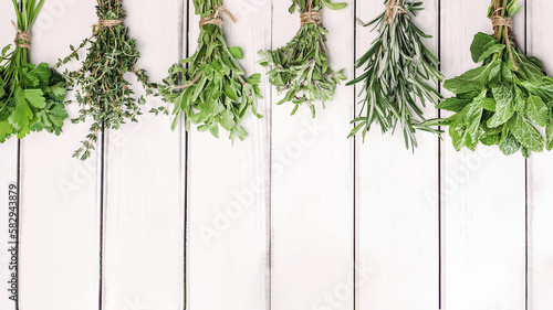 Fresh green herbs on white wooden table, top view