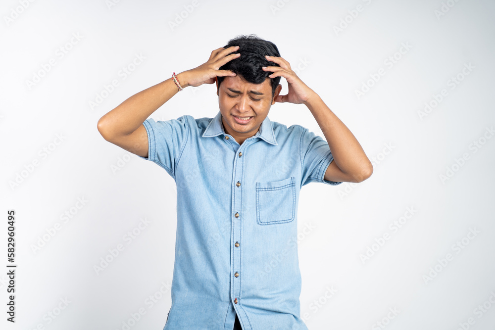 young Asian man holds head while dizzy on isolated background young Asian man holds head while dizzy on isolated background