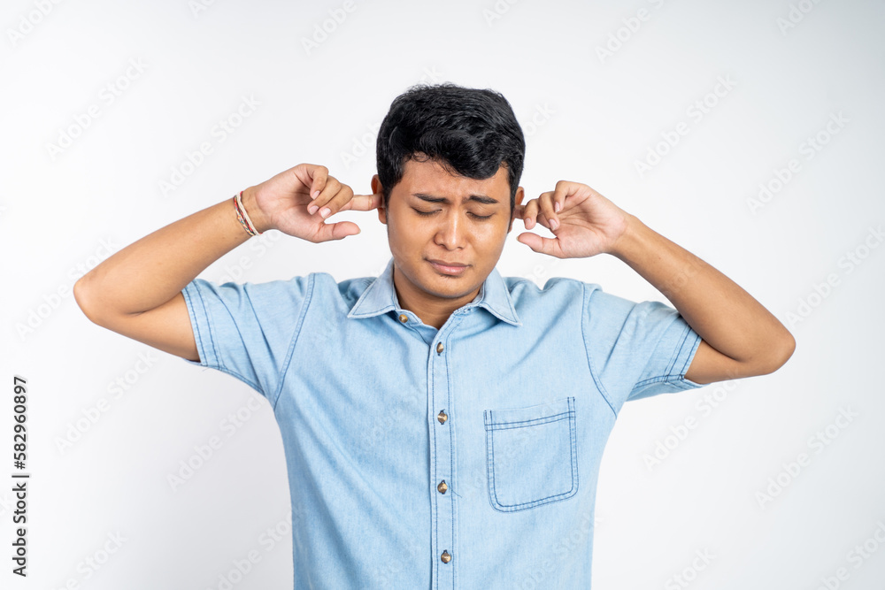 portrait of young Asian man standing with two ears closed in an isolated background portrait of young Asian man standing with two ears closed in an isolated background