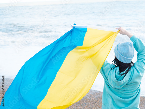 brunnete woman wearing in blue hoodie and blue hat with national flag of Ukraine