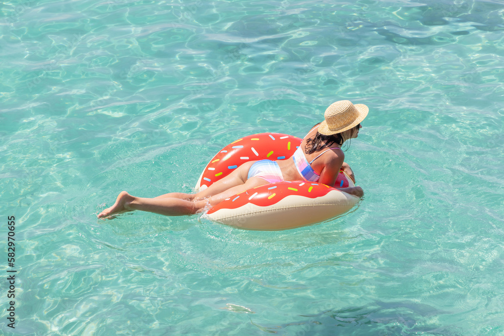 Beautiful woman with inflatable donut in sea