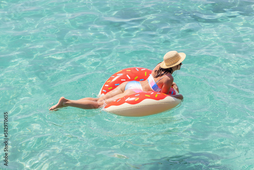 Beautiful woman with inflatable donut in sea
