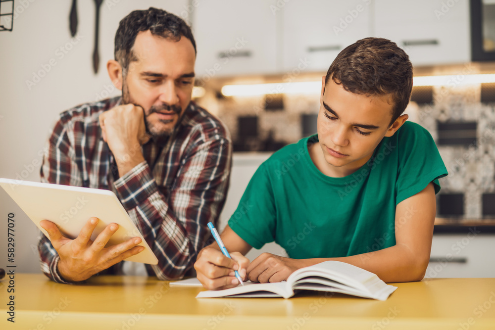 Father is helping his son with learning. They are doing homework together. Father is helping his son with learning. They are doing homework together.