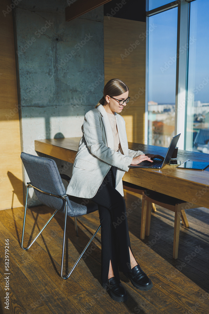 Office work, attractive young female manager working in office, standing in bright workspace using modern laptop computer, young girl having video call via laptop Office work, attractive young female manager working in office, standing in bright workspace using modern laptop computer, young girl having video call via laptop
