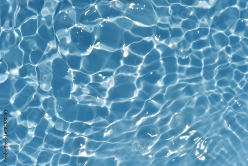 Bluewater waves on the surface ripples blurred. Defocus blurred transparent blue colored clear calm water surface texture with splash and bubbles. Water waves with shining pattern texture background.