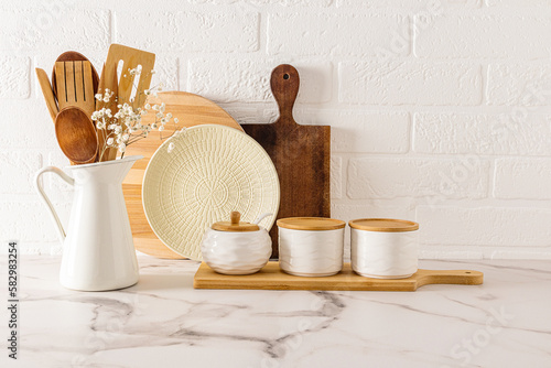 a set of modern kitchen utensils in a minimalist style on a white marble countertop against a brick wall. ECO items.