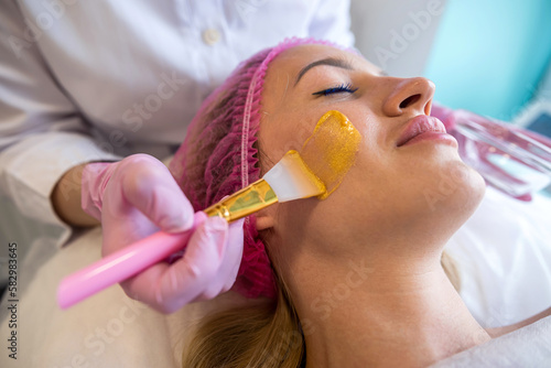 beautiful young girl came to a good spa salon where her beautician applies a mask.