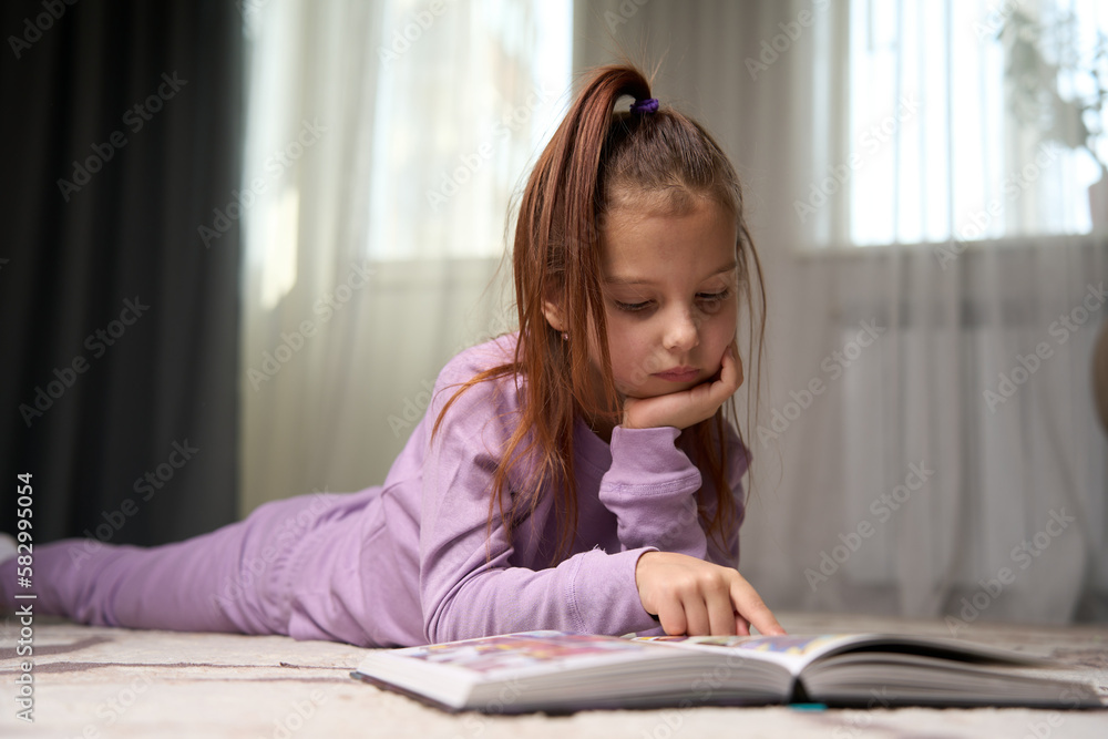 Cute girl lying on the floor and reading a book. Cute girl lying on the floor and reading a book.