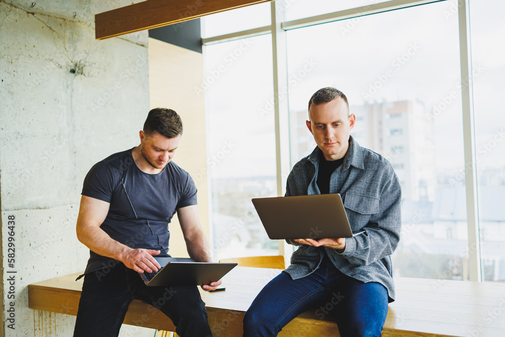 Work of two colleagues sitting together while exchanging ideas with a