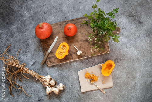 Red kuri squashes, garlic and cilantro lying on gray surface photo