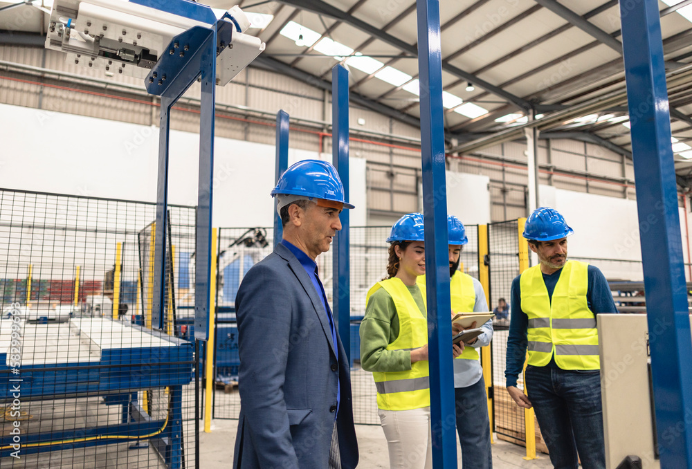Engineer wearing hardhat with colleagues in factory Engineer wearing hardhat with colleagues in factory