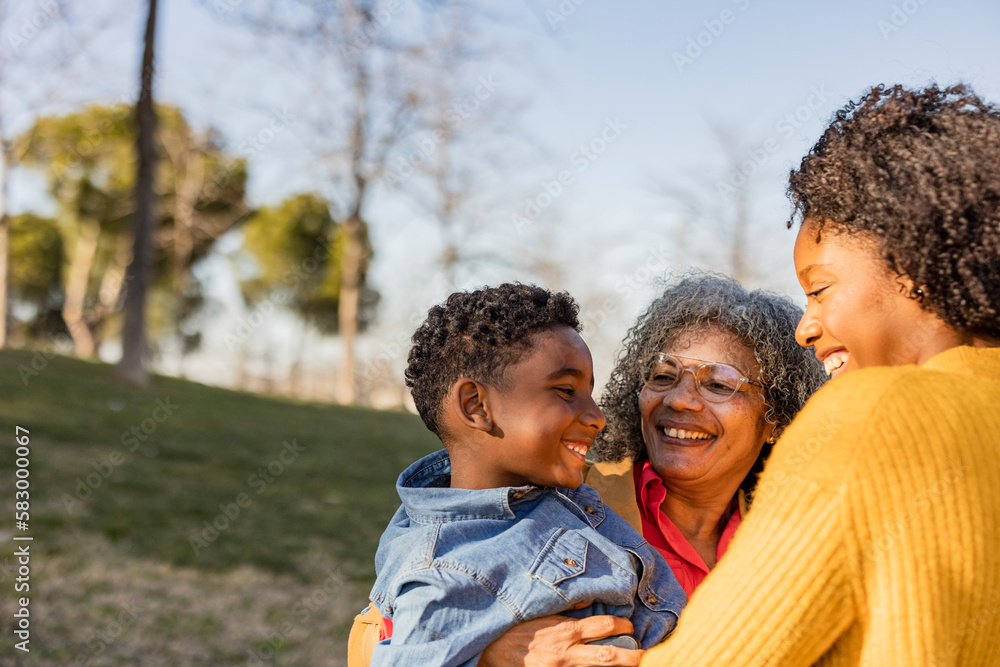 Happy senior woman carrying grandson having fun with mother in park Happy senior woman carrying grandson having fun with mother in park