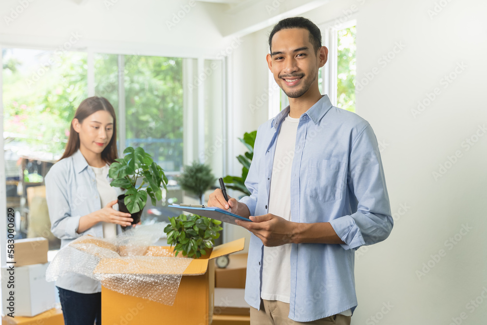 Asian couple checking the list of stuff before packing to cardboard for relocation move out of apartment. Asian couple checking the list of stuff before packing to cardboard for relocation move out of apartment.