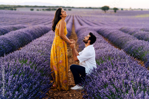 Man proposing woman standing in lavender field photo