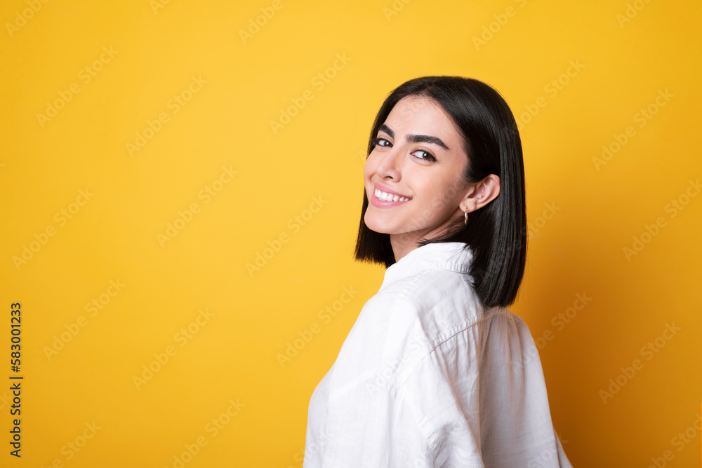 Smiling young woman standing against yellow background Smiling young woman standing against yellow background
