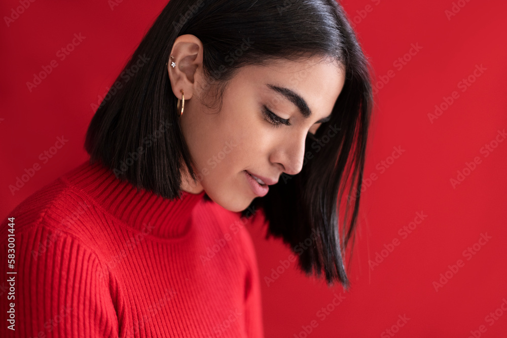 Shy young woman looking down against red background Shy young woman looking down against red background