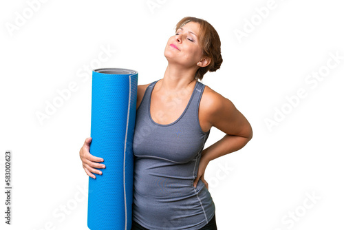 Middle-aged sport woman going to yoga classes while holding a mat over isolated background suffering from backache for having made an effort