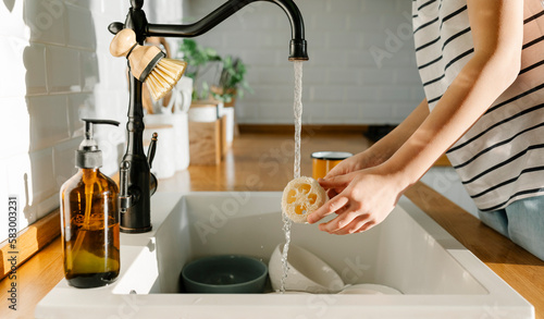 Girl washing loofah in sink at home photo