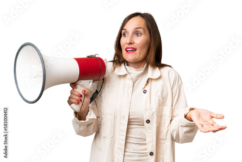 Middle-aged caucasian woman over isolated background holding a megaphone and with surprise facial expression