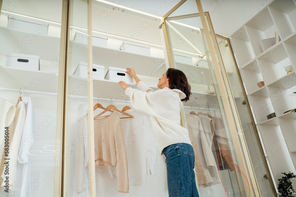 Young woman taking out box from closet Young woman taking out box from closet