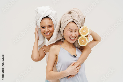 Two smiling women hugging while posing with lemon isolated over white background