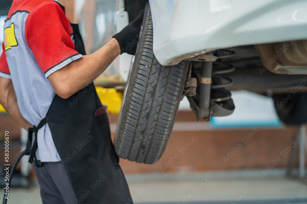 Naklejka premium Auto mechanic in tire change service center fixing wheel bolts, professional handyman