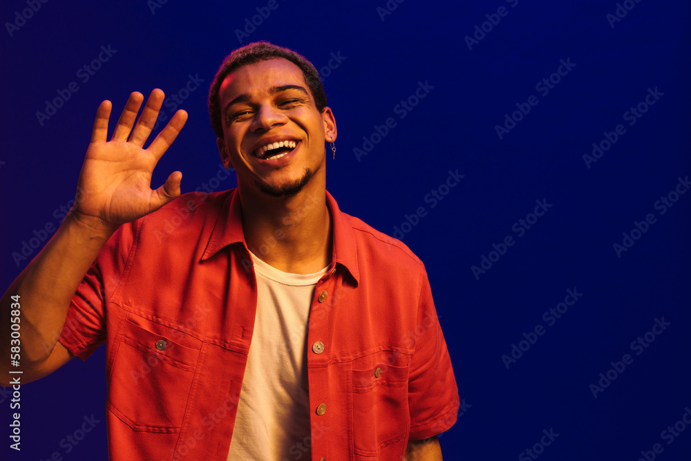 African man waving hand isolated over blue neon background