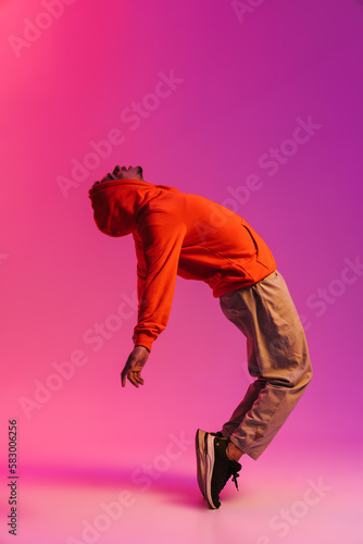 African man dancing standing on toes isolated over pink neon background