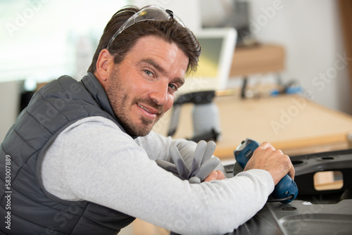 man mechanical worker repairing with electric grider photo